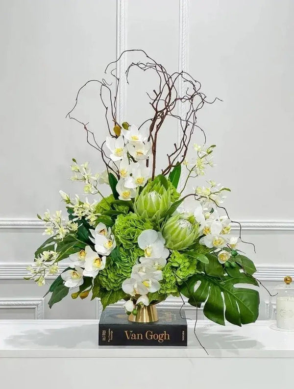 Elegant white funeral bouquet with roses, lilies, and greenery in a glass vase, perfect for memorial services and expressing sympathy.