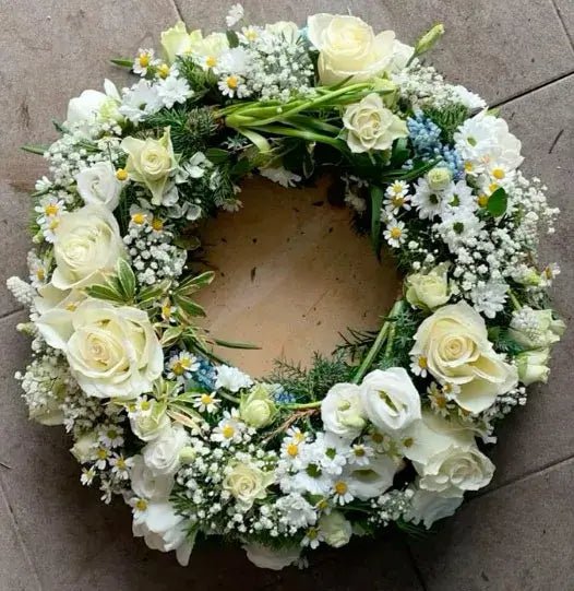 Classic white funeral wreath with roses, daisies, baby's breath, and greenery – elegant floral tribute for funerals and memorial services