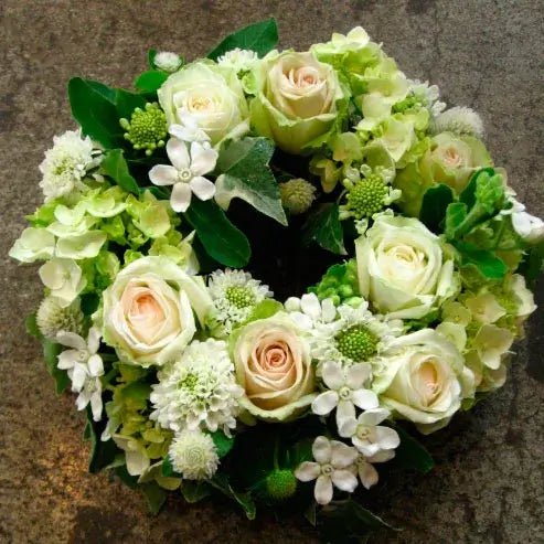 Small funeral wreath with pale pink roses, white hydrangeas, delicate filler flowers, and greenery – elegant floral tribute for funerals and memorial services